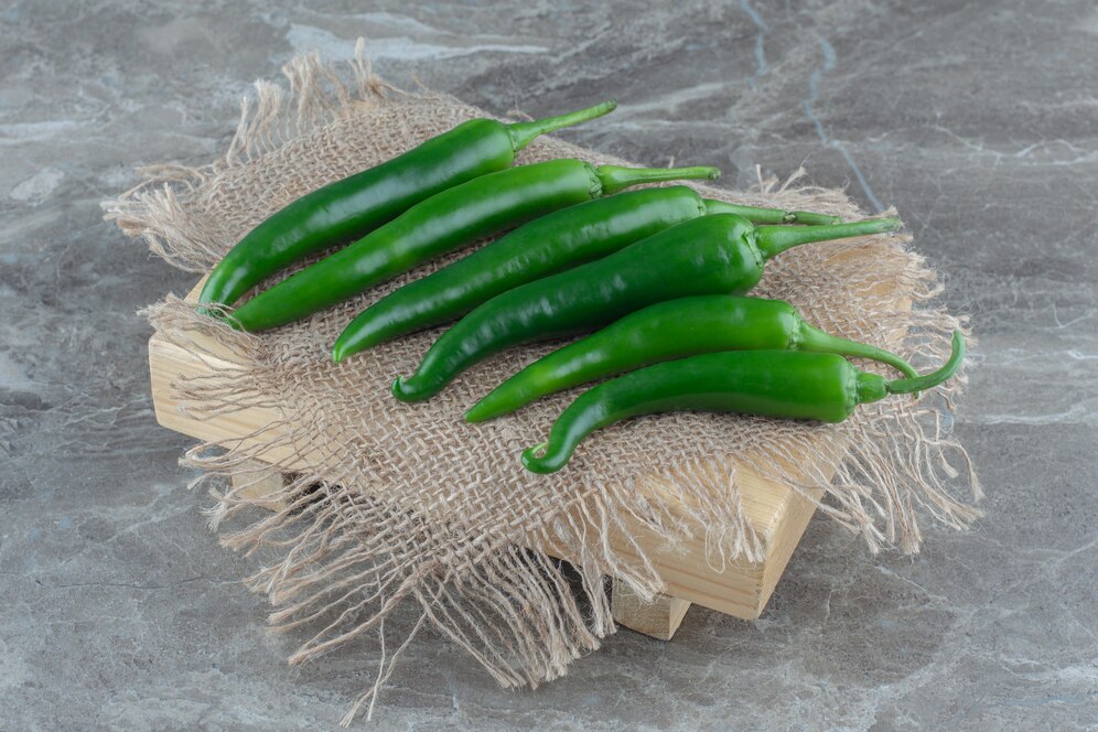 pile-green-hit-chili-peppers-n-sack-grey-surface_114579-86482